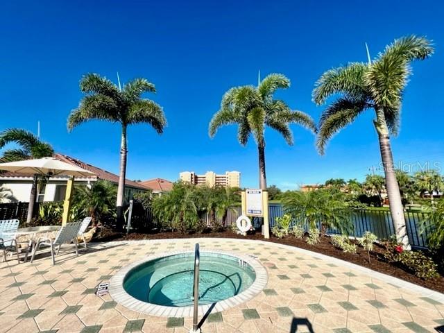 A circular hot tub sits on a paved patio surrounded by palm trees and buildings — 3181 MATECUMBE KEY ROAD UNIT 10, PUNTA GORDA, FL