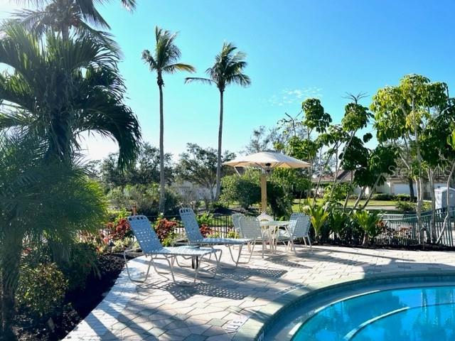 A swimming pool with lounge chairs and a patio umbrella surrounded by palm trees — 3181 MATECUMBE KEY ROAD UNIT 10, PUNTA GORDA, FL