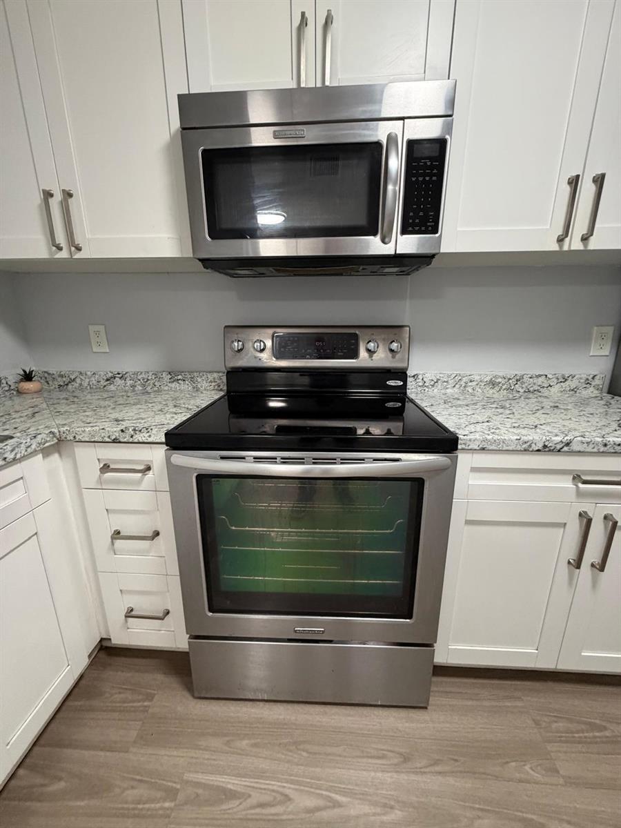 A kitchen features white cabinets, granite countertops, and stainless steel appliances — 615 S State Road 7 # 1d, Margate FL 33068, MARGATE, FL