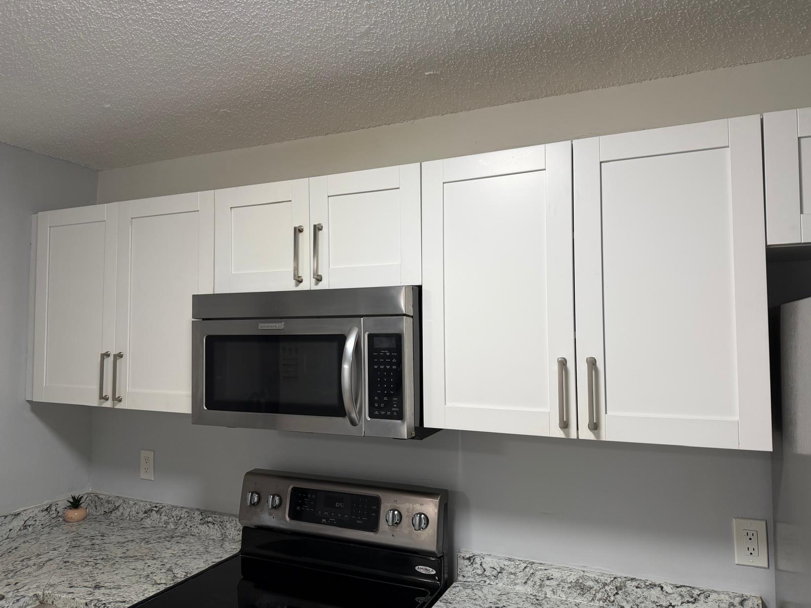 A kitchen features white shaker cabinets, stainless steel appliances, and speckled granite countertops — 615 S State Road 7 # 1d, Margate FL 33068, MARGATE, FL