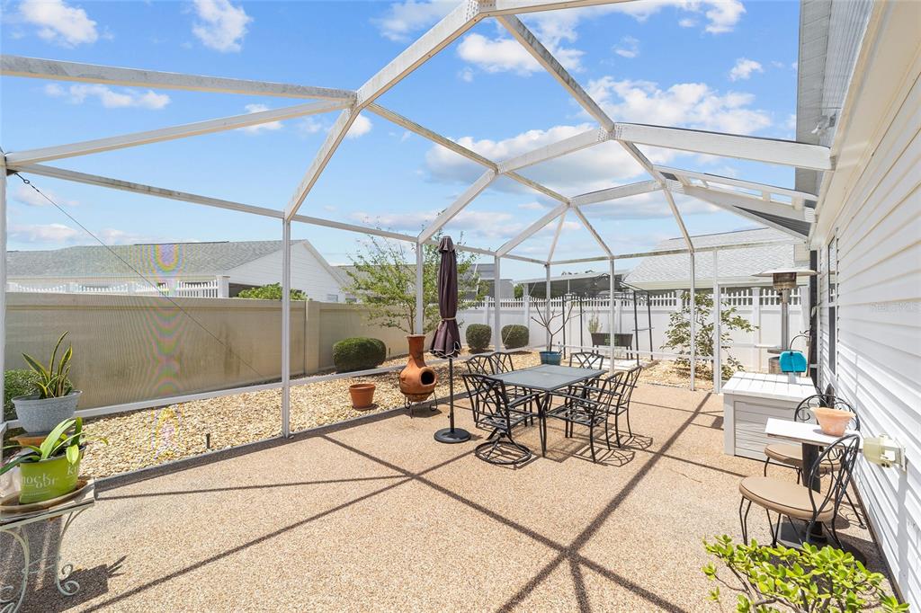 A screened-in patio features a dining set, gravel landscaping, and a white privacy fence — 418 FLOSSMOOR COURT, THE VILLAGES, FL