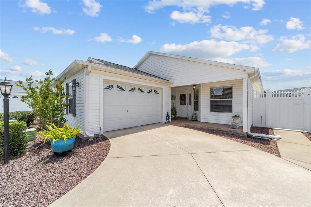 A white single-story house with a garage, concrete driveway, and a white privacy fence — 418 FLOSSMOOR COURT, THE VILLAGES, FL