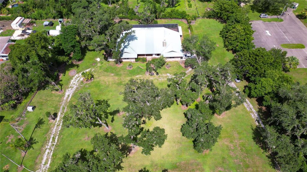 An aerial view shows a house with a metal roof surrounded by trees and grass — 914 S MILLER ROAD, VALRICO, FL