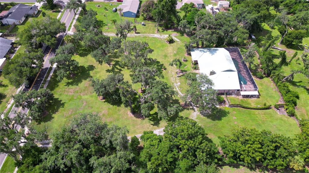 An aerial view shows a house with a pool enclosure surrounded by trees and grass — 914 S MILLER ROAD, VALRICO, FL