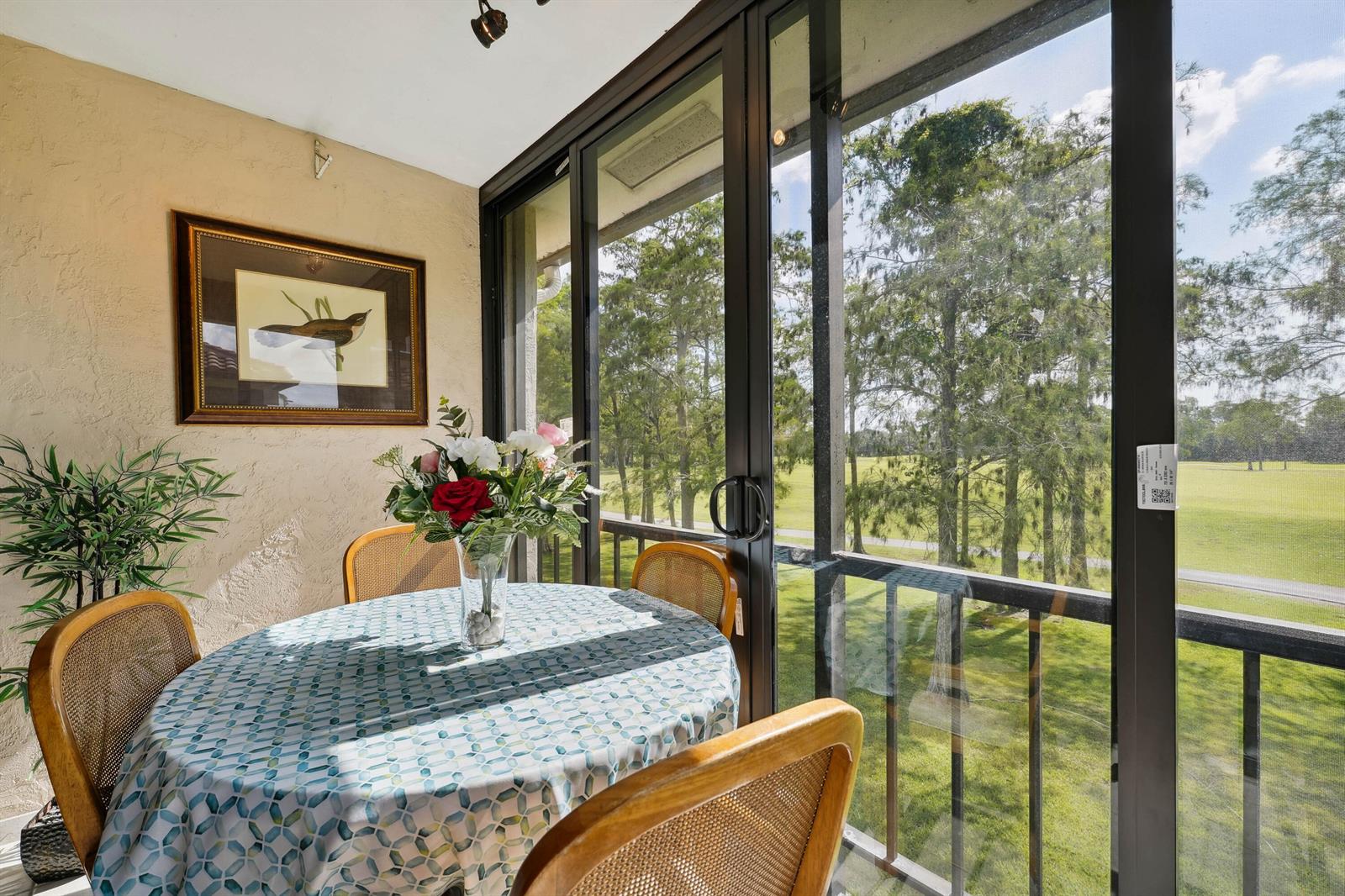 A sunroom with a round dining table, wicker chairs, and sliding glass doors overlooking greenery — 21650 Juego Circle # 24b, Boca Raton FL 33433, BOCA RATON, FL