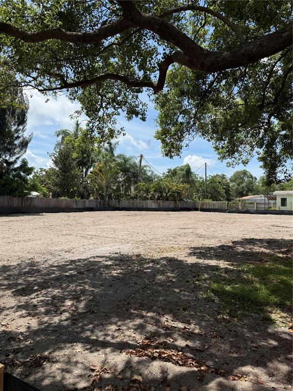 A large, cleared, sandy residential lot is enclosed by a wooden fence under tree branches — 3531 DR MLK JR. DRIVE, ST PETERSBURG, FL