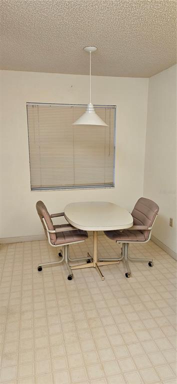 A small dining area features a white table, two rolling chairs, and a pendant light — 12027 HOOSIER COURT UNIT 201, HUDSON, FL