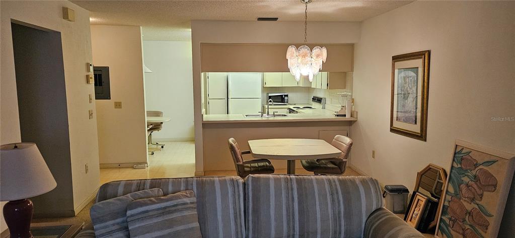 A living room with a striped sofa faces a kitchen with a breakfast table — 12027 HOOSIER COURT UNIT 201, HUDSON, FL
