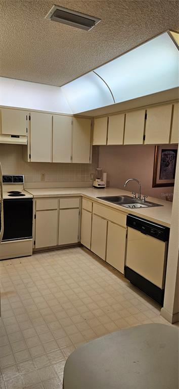 A kitchen features off-white cabinets, a black stove, a dishwasher, and a tiled floor — 12027 HOOSIER COURT UNIT 201, HUDSON, FL