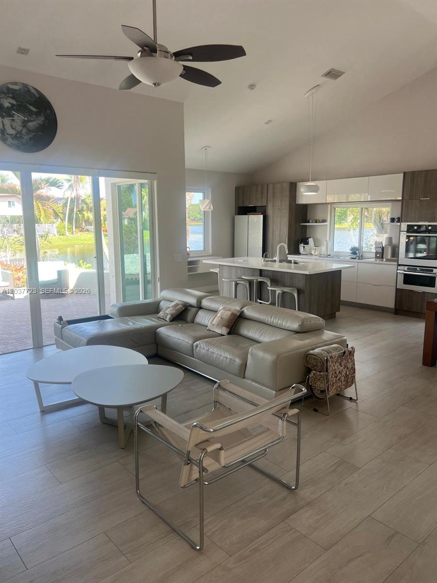 An open-concept living room and kitchen feature light wood flooring, a sectional sofa, and water views — 1130 Spyglass, Weston FL 33326, WESTON, FL