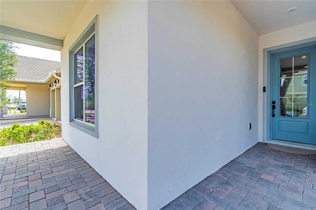 A covered entryway features a blue front door, a window, and gray paver flooring — 10156 BALLAST DRIVE, ORLANDO, FL