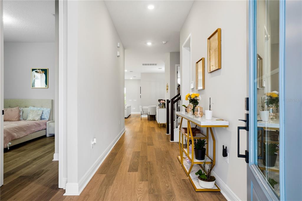 A hallway with hardwood floors leads to a dining area, featuring a console table — 10156 BALLAST DRIVE, ORLANDO, FL