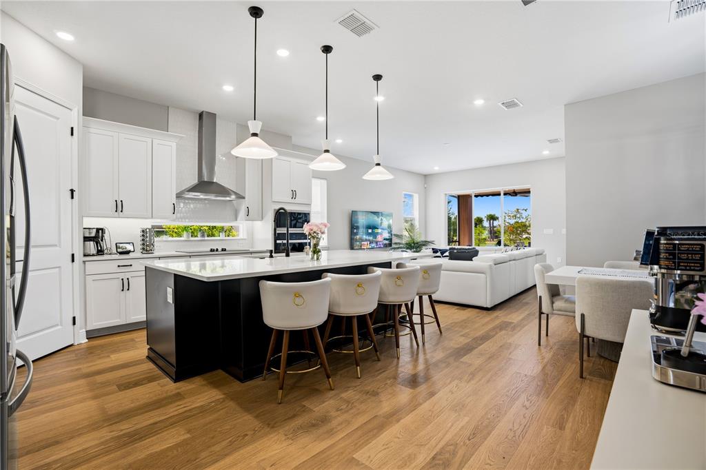A modern kitchen features a large black island, white cabinetry, and wood flooring — 10156 BALLAST DRIVE, ORLANDO, FL