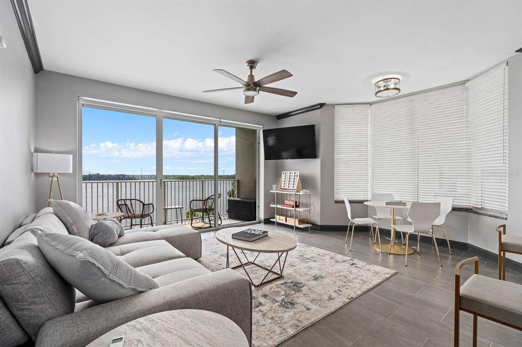 A living room with a gray sectional, dining area, and a balcony overlooking the water — 13415 BLUE HERON BEACH DRIVE UNIT 410, ORLANDO, FL