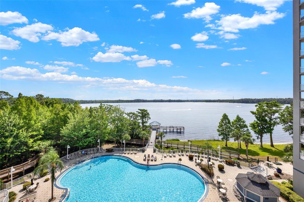 A high-angle view of a swimming pool, wooden pier, and lake under a blue sky — 13415 BLUE HERON BEACH DRIVE UNIT 410, ORLANDO, FL
