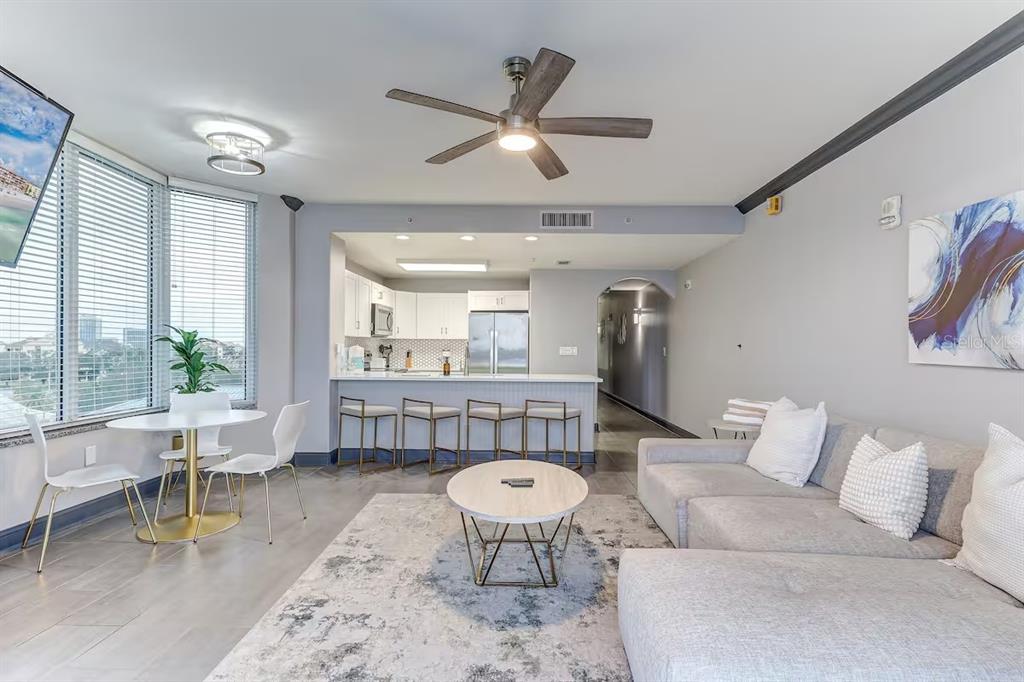 An open-concept living room and kitchen feature a sectional sofa, dining area, and breakfast bar — 13415 BLUE HERON BEACH DRIVE UNIT 410, ORLANDO, FL