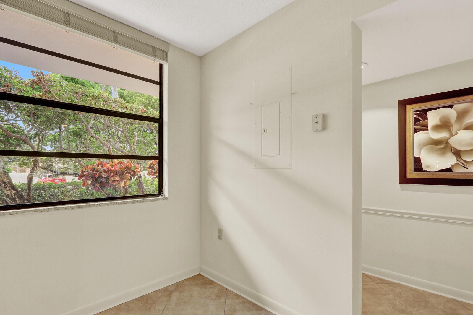 A room with tile flooring, a window overlooking trees, and a wall-mounted electrical panel — 3636 WHITEHALL Drive # 105, West Palm Beach FL 33401, WEST PALM BEACH, FL