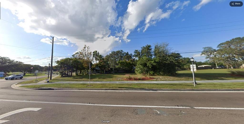 This street-level view shows a grassy, tree-lined vacant lot next to a paved road — N/A, POLK CITY, FL