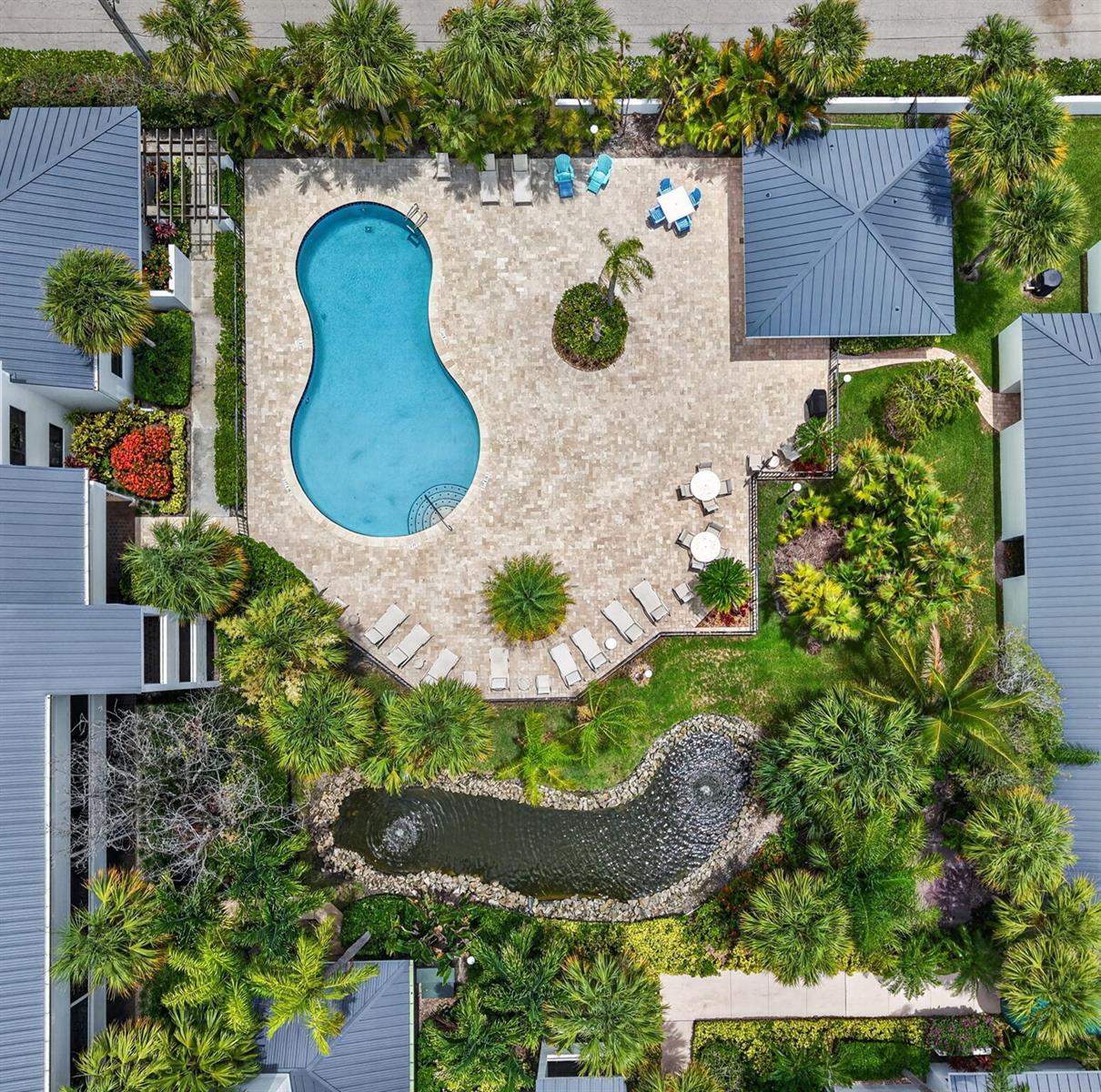 An aerial view shows a swimming pool, a pond, and patio furniture surrounded by landscaping — 200 Waterway Road # 104, Tequesta FL 33469, TEQUESTA, FL