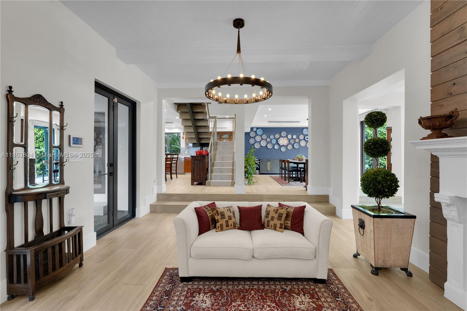 A white sofa sits on a patterned rug in a living room with light wood floors — 4475 N Meridian Ave, Miami Beach FL 33140, MIAMI BEACH, FL