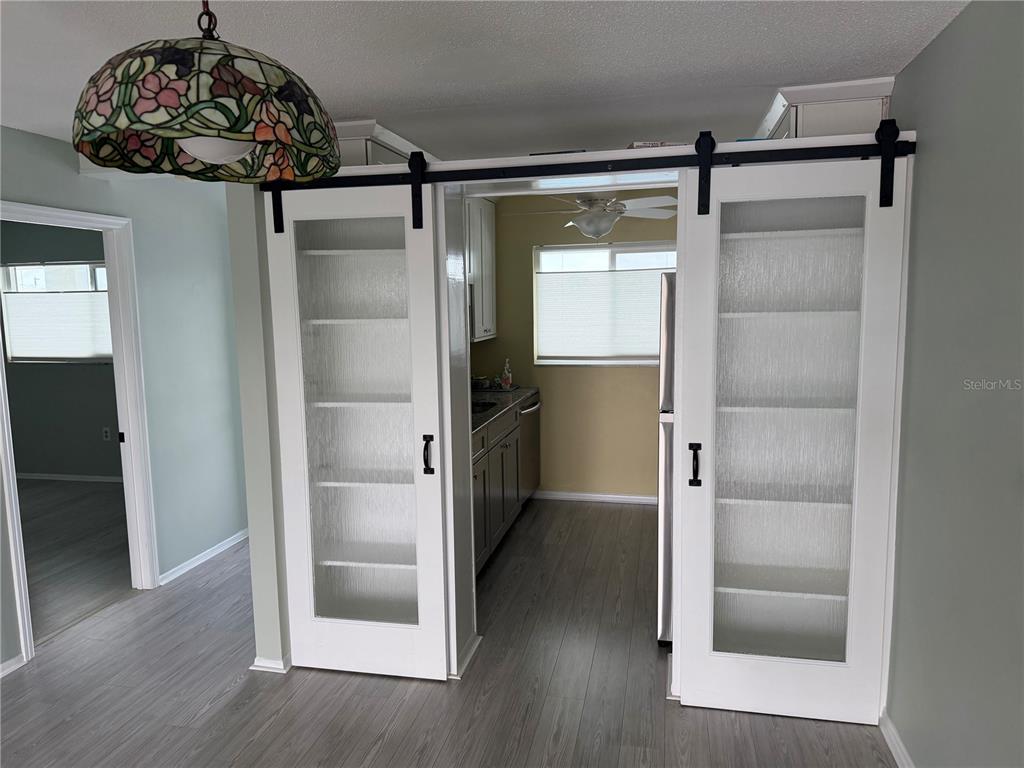 A kitchen is visible through two white sliding barn doors with glass panels — 649 TAMIAMI TRAIL S UNIT 310, VENICE, FL