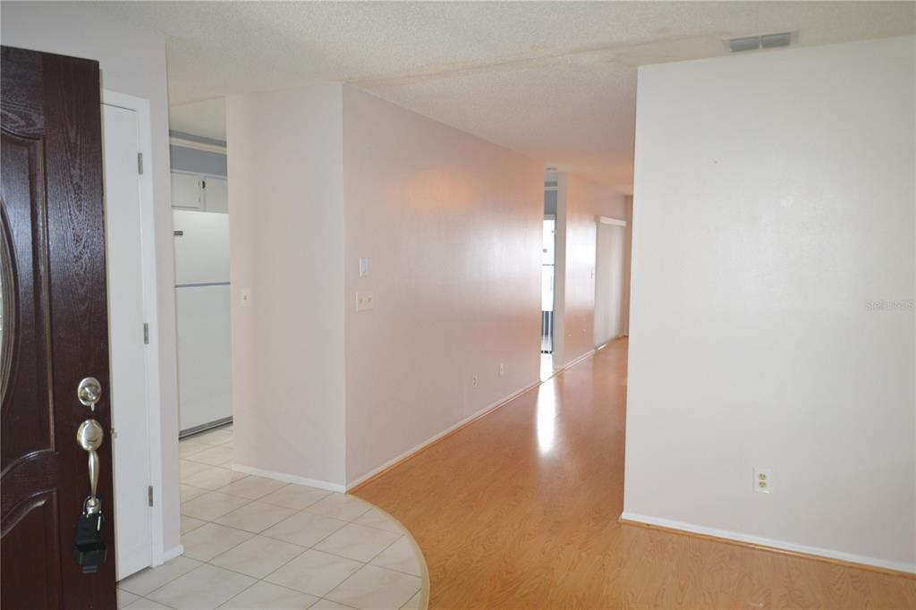 An entryway with tiled flooring transitions into a hallway with light wood-look flooring — 2001 DOVER COURT, OLDSMAR, FL