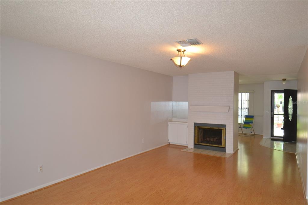 A living room with light wood flooring, a white brick fireplace, and a front door — 2001 DOVER COURT, OLDSMAR, FL