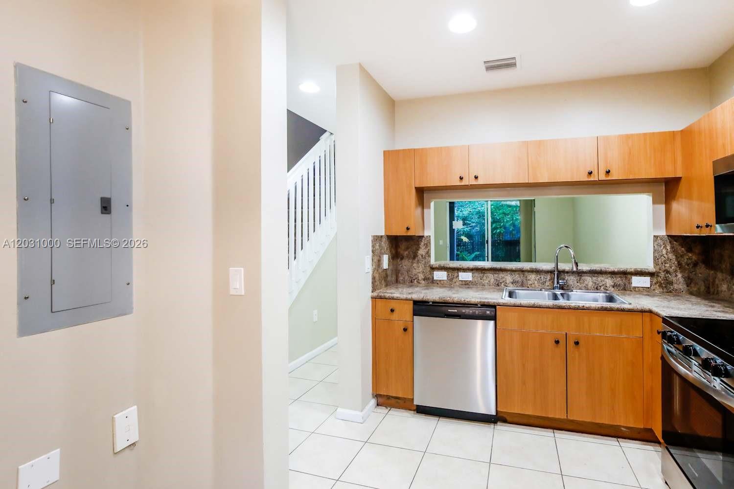 A kitchen features light wood cabinets, stainless steel appliances, and a window above the sink — MIRAMAR, FL