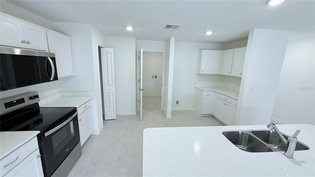 A kitchen features white cabinets, stainless steel appliances, a center island, and light tile flooring — 52 PRINCETON LANE, PALM COAST, FL