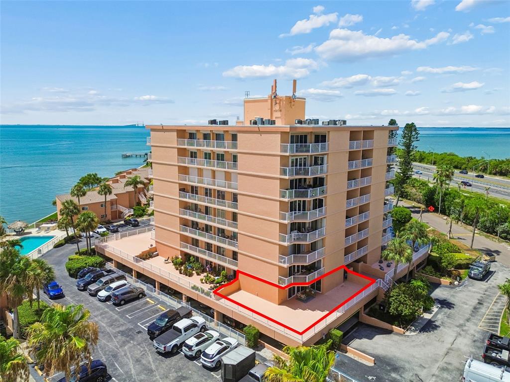 An aerial view shows a multi-story peach-colored apartment building with a large highlighted terrace — 7430 SUNSHINE SKYWAY LANE S UNIT 201, ST PETERSBURG, FL
