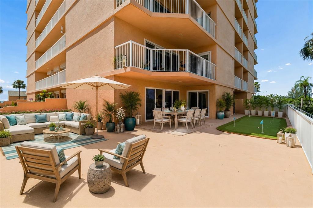 A large outdoor patio features a seating area, dining set, and a small putting green — 7430 SUNSHINE SKYWAY LANE S UNIT 201, ST PETERSBURG, FL