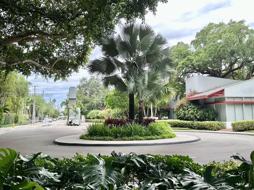 A circular driveway features a central palm tree island with lush landscaping and a building — 700 NE 63rd St # D205, Miami FL 33138, MIAMI, FL