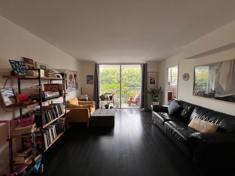A living room features dark wood floors, a black leather sofa, and a balcony view — 700 NE 63rd St # D205, Miami FL 33138, MIAMI, FL