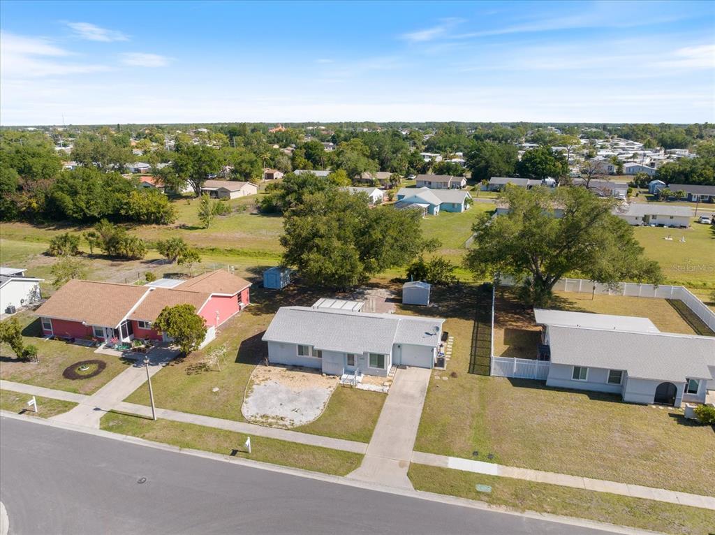 An aerial view shows three single-story houses with driveways and lawns in a suburban neighborhood — 5494 GABO ROAD, NORTH PORT, FL