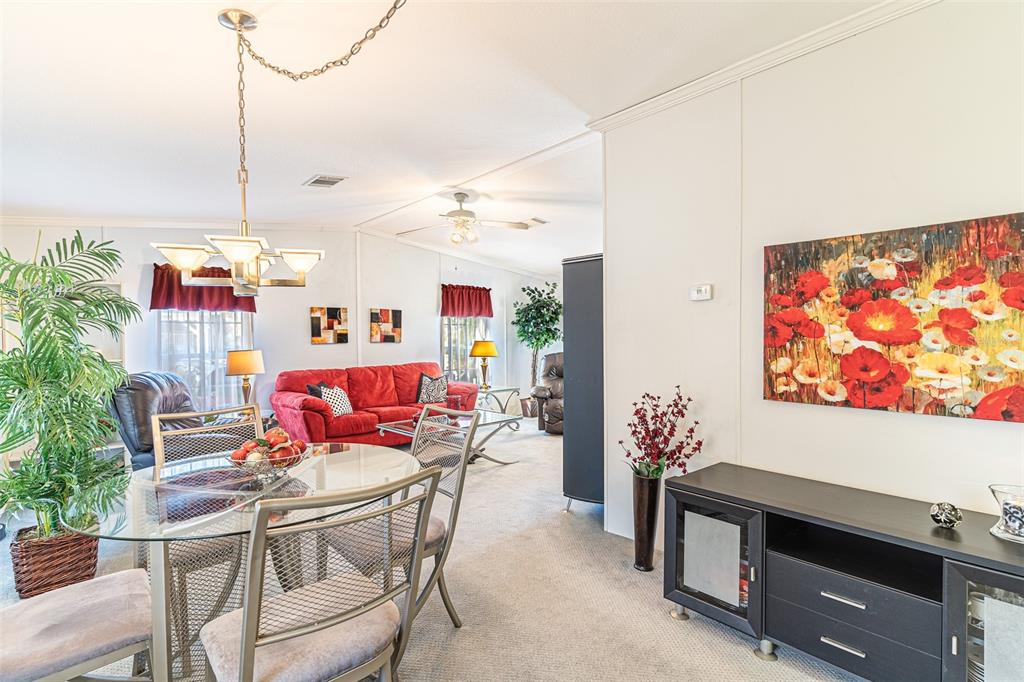 A dining area with a glass table leads into a living room with a red sofa — 13 SILVERSIDES STREET, LAKE WALES, FL