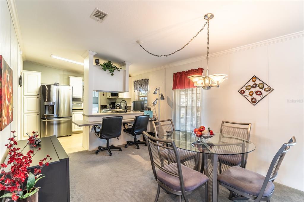 A dining area with a glass table and chairs sits adjacent to a kitchen counter — 13 SILVERSIDES STREET, LAKE WALES, FL