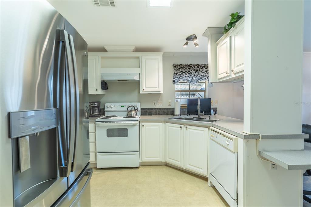 A kitchen features white cabinets, a stainless steel refrigerator, a white stove, and a dishwasher — 13 SILVERSIDES STREET, LAKE WALES, FL