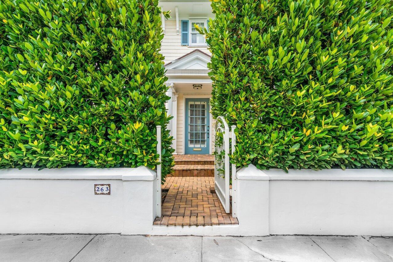 A blue front door is framed by tall hedges behind a white wall and gate — 263 Park Avenue, Palm Beach FL 33480, PALM BEACH, FL