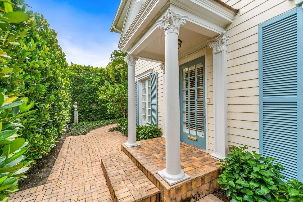 A brick walkway leads to a covered porch with white columns and a blue door — 263 Park Avenue, Palm Beach FL 33480, PALM BEACH, FL