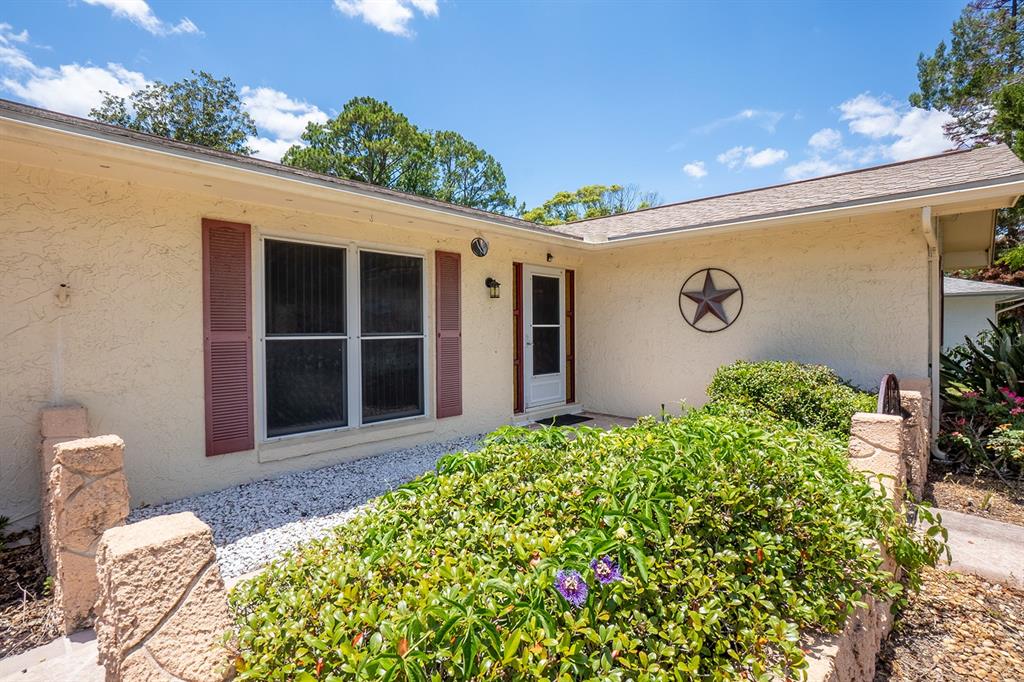 The exterior of a single-story house features cream stucco walls, red shutters, and a star decoration — 113 FARRAGUT DRIVE, PALM COAST, FL
