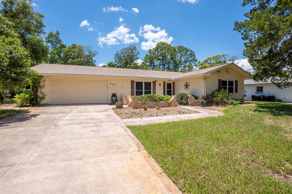 A single-story house with a beige exterior, a two-car garage, and a stone planter — 113 FARRAGUT DRIVE, PALM COAST, FL