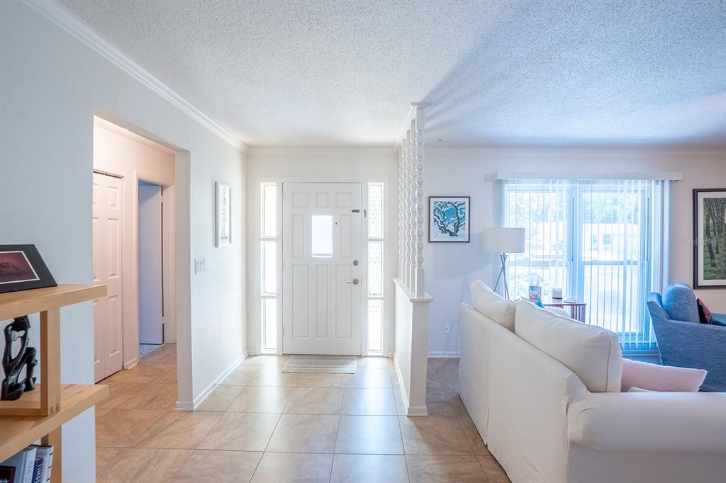 A bright entryway with tile flooring leads to a white front door and living area — 113 FARRAGUT DRIVE, PALM COAST, FL