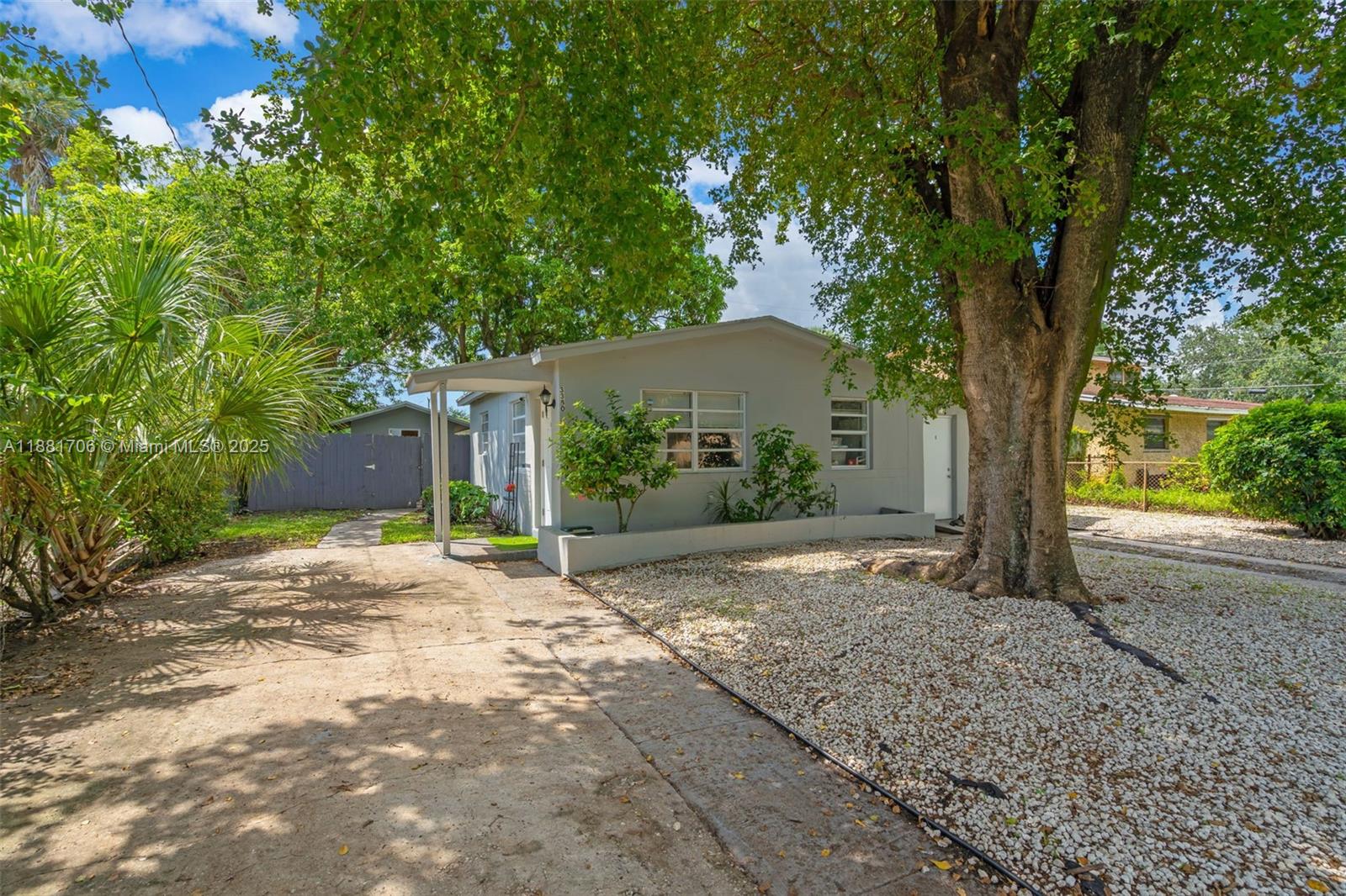 A single-story house with a concrete driveway, gravel front yard, and a large tree — 3380 NW 8th Pl, Lauderhill FL 33311, LAUDERHILL, FL