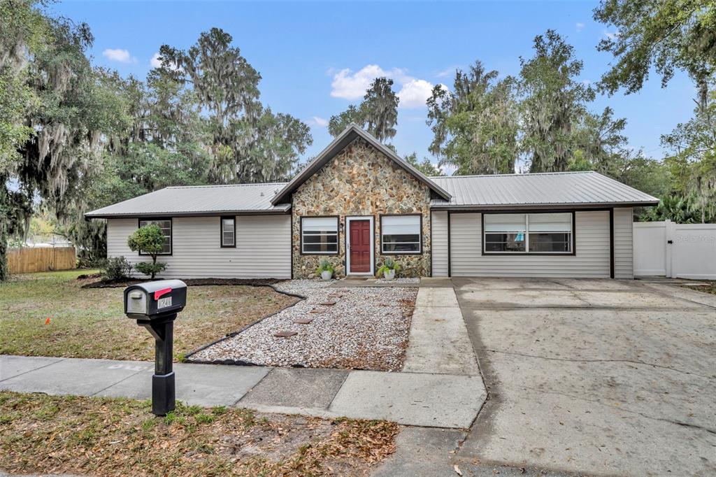 A single-story house with a stone facade, metal roof, and a gravel walkway — 1240 W VOORHIS AVENUE, DELAND, FL