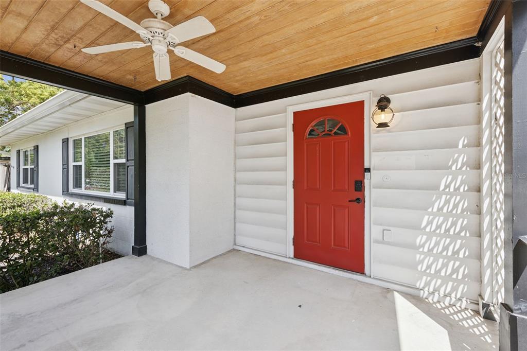 A covered front porch features a red door, wood-paneled ceiling, and a ceiling fan — 1911 CANTON STREET, ORLANDO, FL