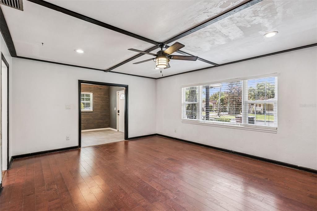 A living room with dark wood flooring, white walls, and a ceiling fan with beams — 1911 CANTON STREET, ORLANDO, FL