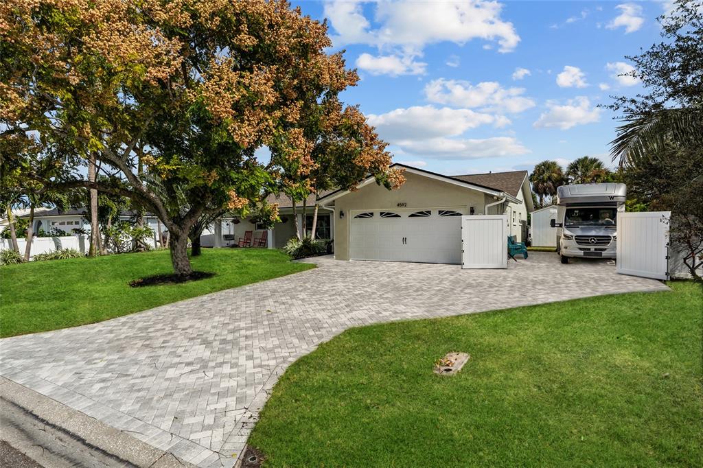 A single-story house with a paved driveway, a large front lawn, and mature trees — 4592 40TH STREET S, ST PETERSBURG, FL
