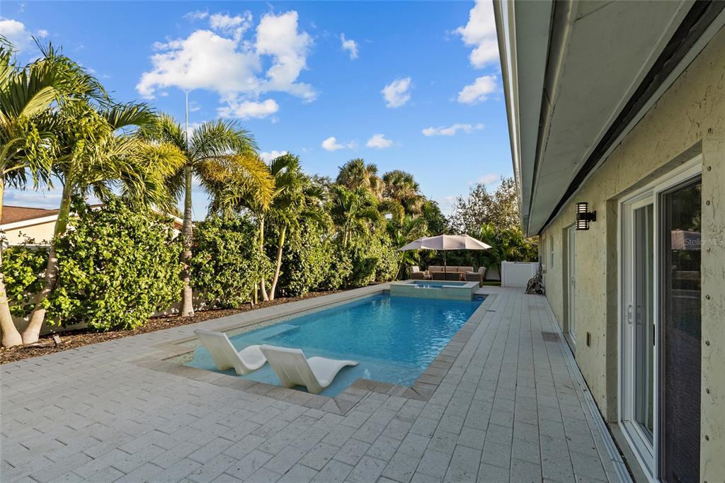 A backyard features a rectangular swimming pool with lounge chairs and a raised spa area — 4592 40TH STREET S, ST PETERSBURG, FL
