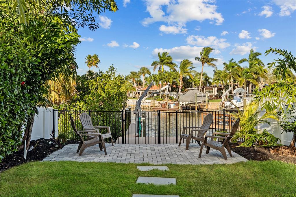 A paved patio with four chairs overlooks a canal with a boat lift and dock — 4592 40TH STREET S, ST PETERSBURG, FL