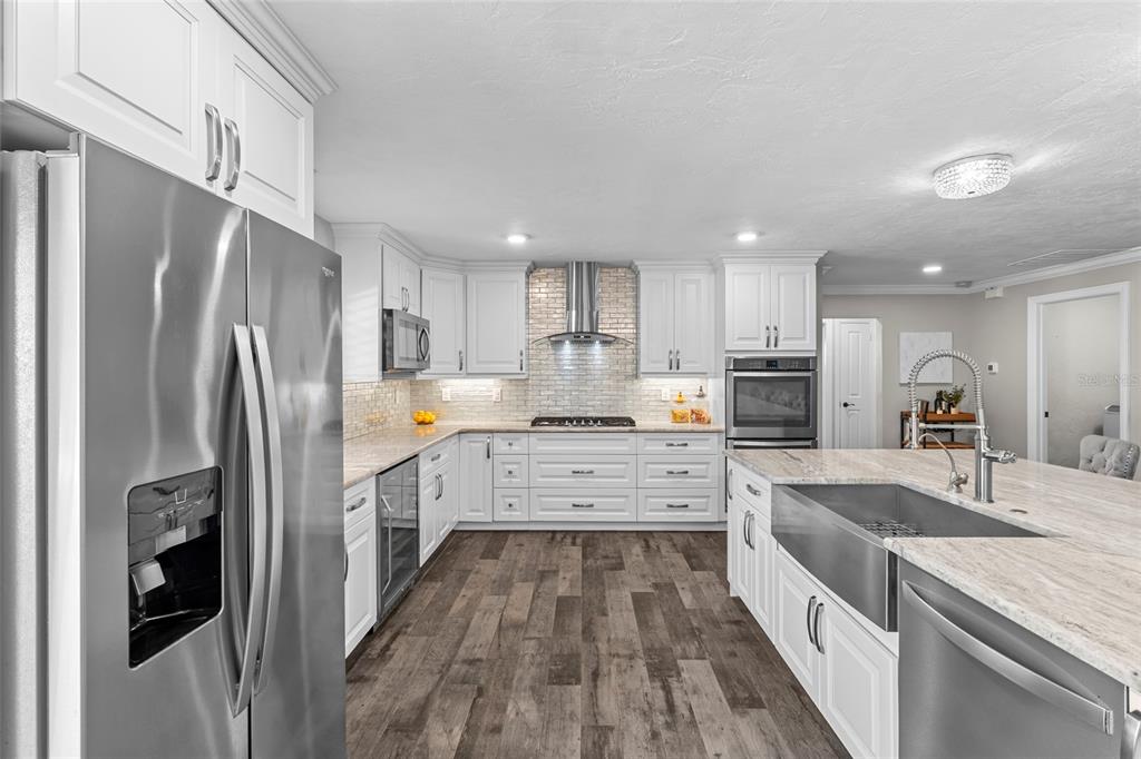 A modern kitchen features white cabinetry, stainless steel appliances, a large island, and wood flooring — 4592 40TH STREET S, ST PETERSBURG, FL